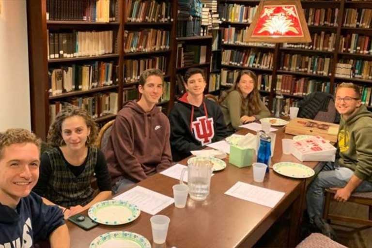 Study group pose for photo at long table in library.