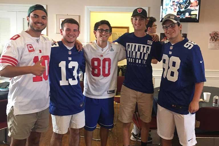Group of young white males pose with sports jerseys.