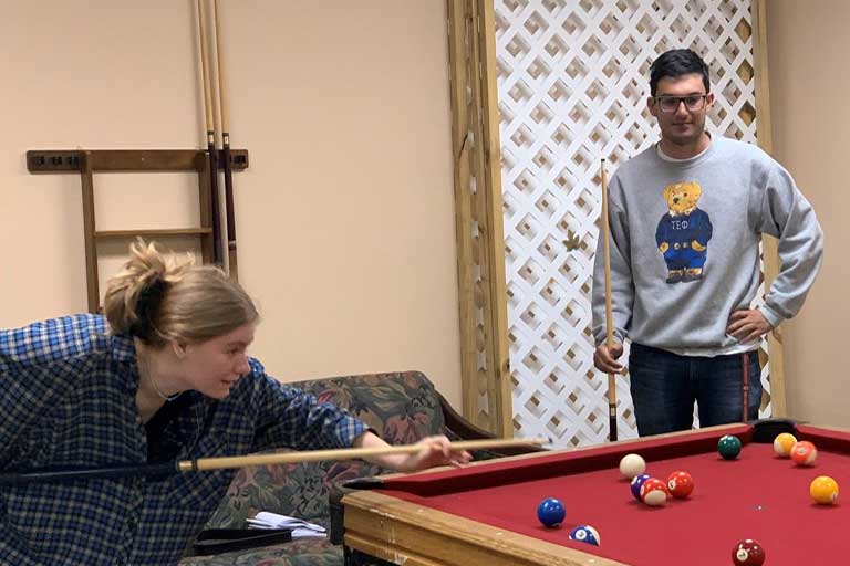 Two people engage in a game of billards 
